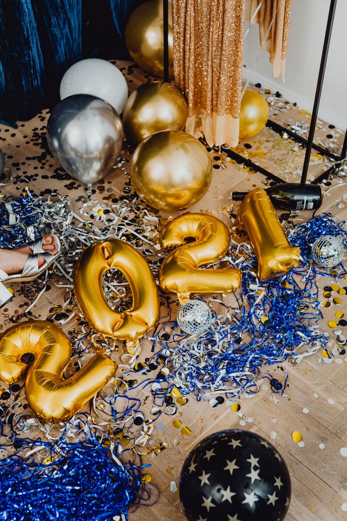 Gold and silver balloons with confetti celebrating New Year 2021 indoors.